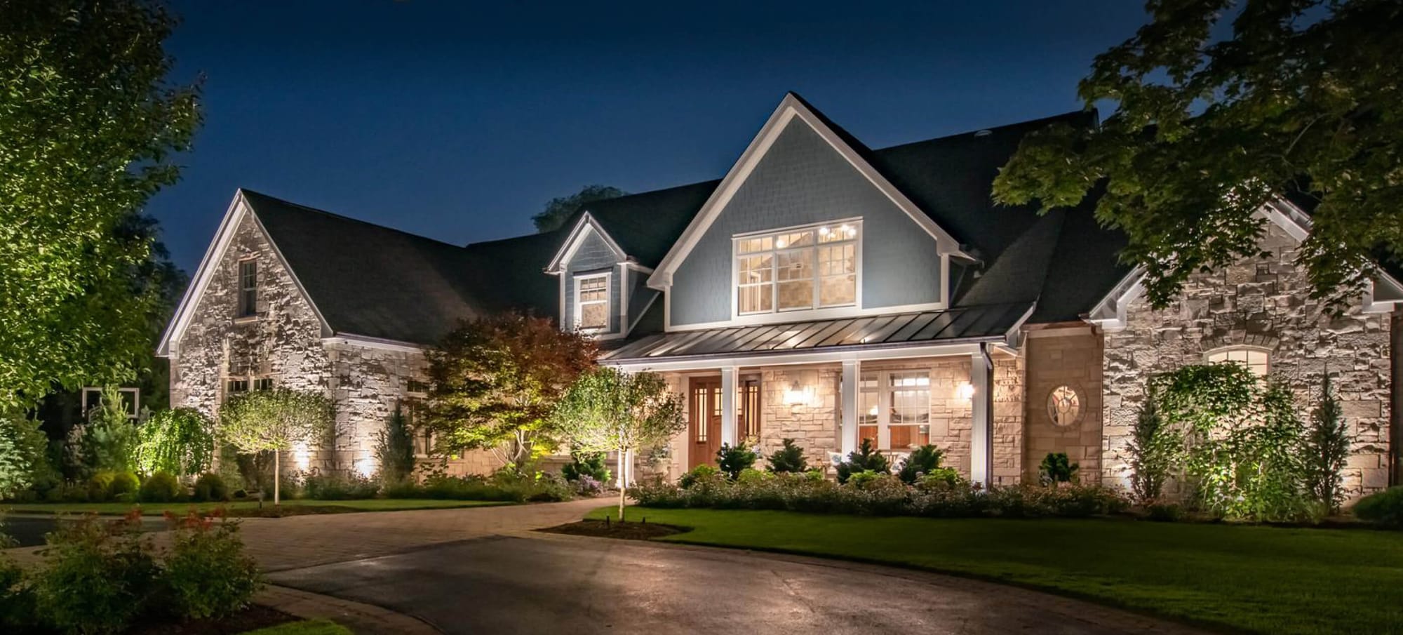 Home at night with warm landscape uplighting and path lights